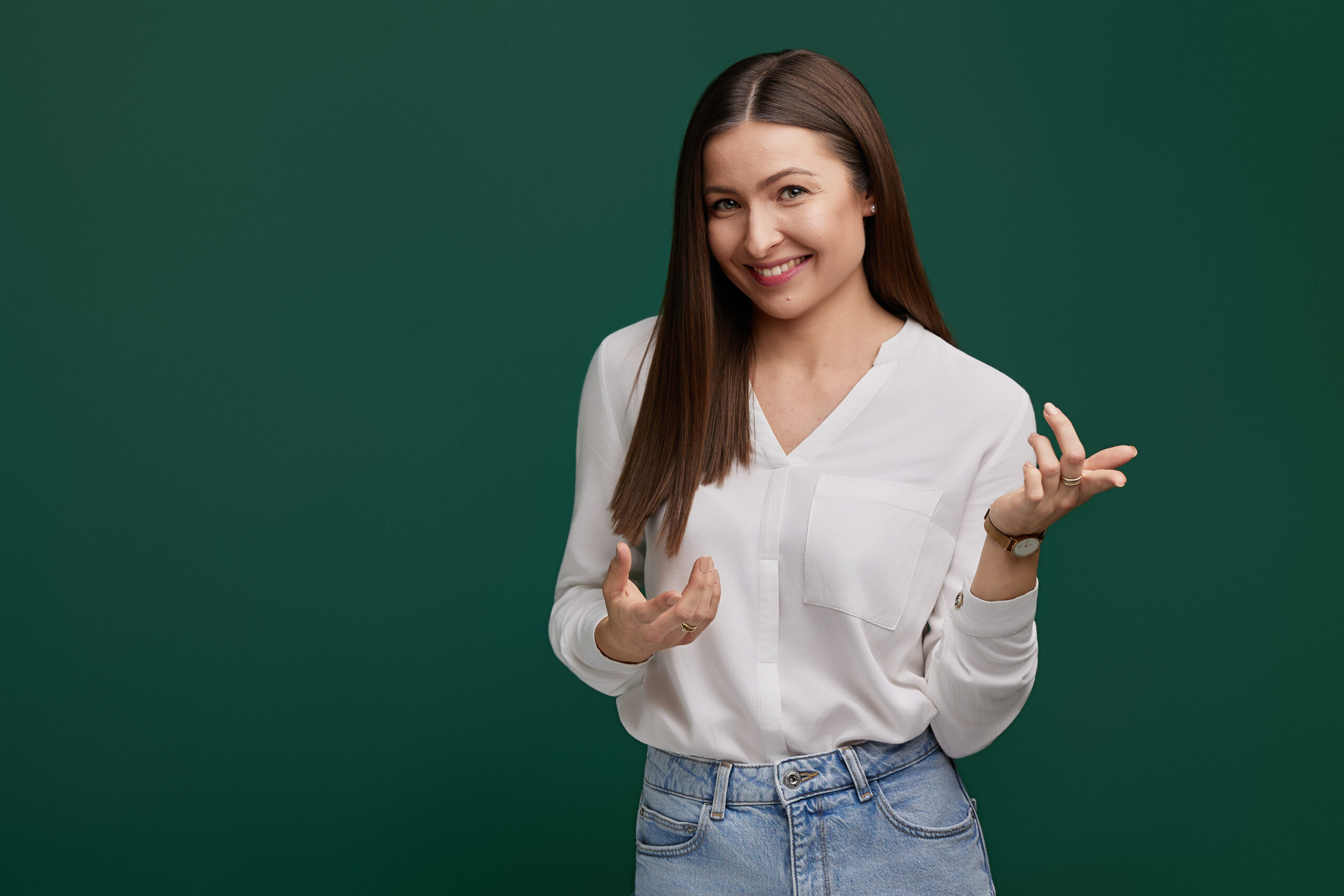 Justyna Bajkowska w białej koszuli gestykuluje podczas rozmowy na zielonym tle