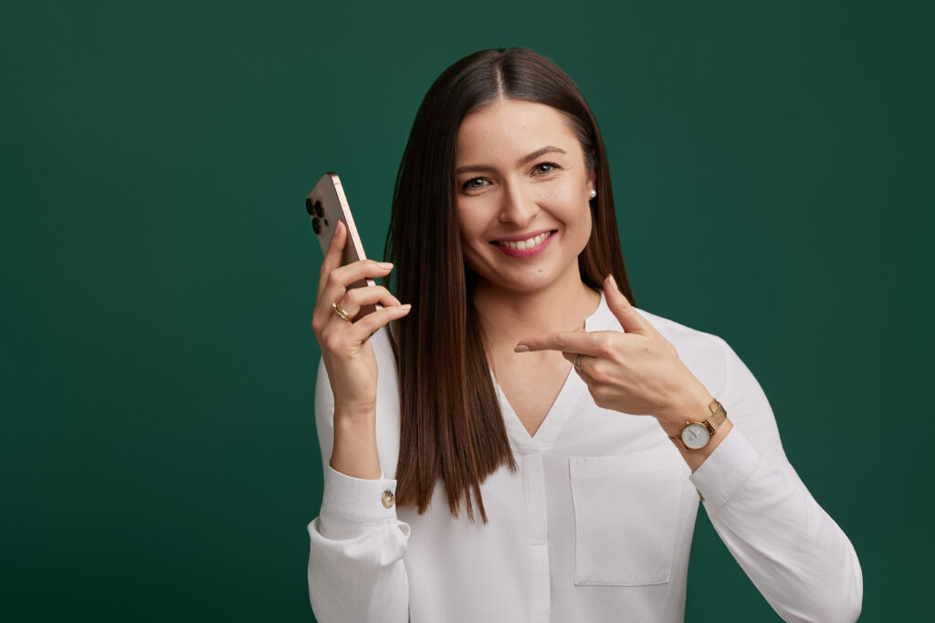 Organizatorka z telefonem na zielonym tle wskazuje na aparat – bezpłatna rozmowa wstępna